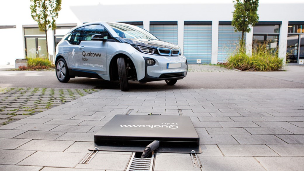 Alt text: An electric car parked on the street in front of a wireless charging point.